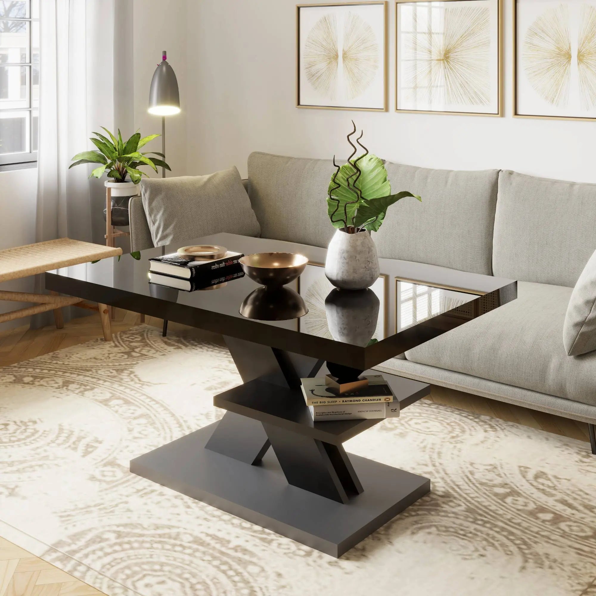 A sleek black coffee table with a grey X-shaped base, styled with books and plants in a minimalist living room.