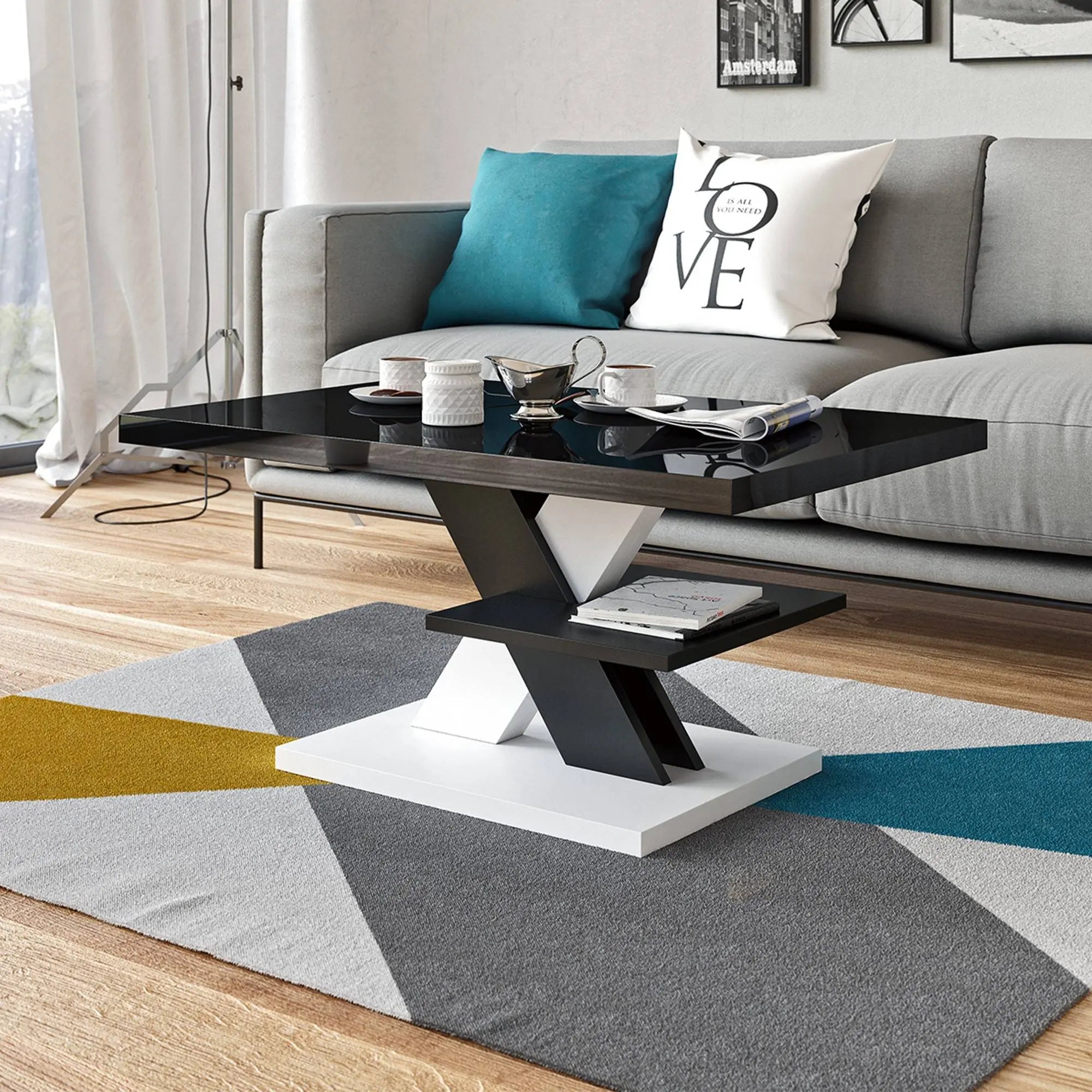 Glossy black coffee table with a white X-shaped base, styled in a living room with geometric accents and colourful decor.